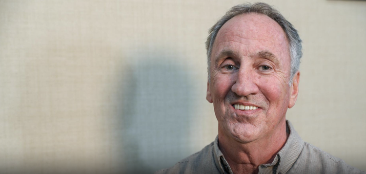 Smiling middle-aged man with gray hair and a checkered shirt.
