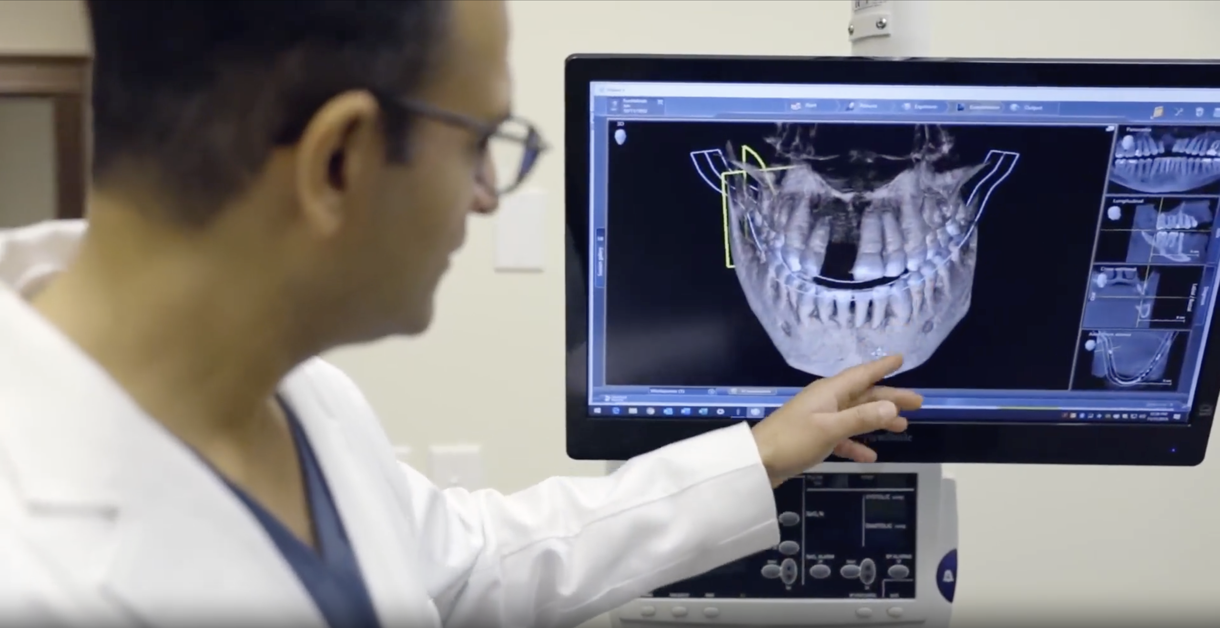 Medical professional examining a 3D scan of a human skull and jaw on a computer screen.