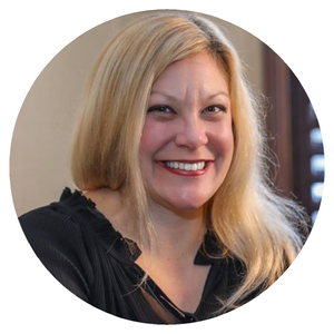 A woman with blonde hair smiling in an indoor setting